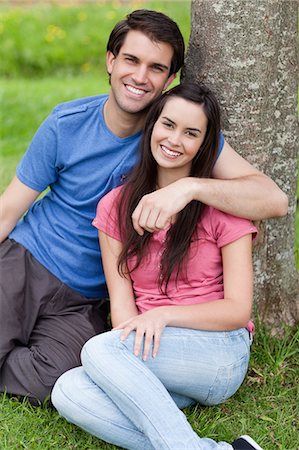 Young happy couple sitting down while leaning against a tree in the countryside Stock Photo - Premium Royalty-Free, Code: 6109-06003453
