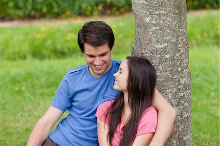 Young smiling couple leaning together against a tree in the countryside Stock Photo - Premium Royalty-Free, Code: 6109-06003455