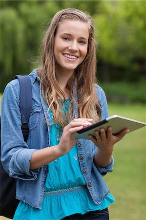 students tablets outside - Young happy girl touching her tablet computer while carrying her backpack in a park Stock Photo - Premium Royalty-Free, Code: 6109-06003403