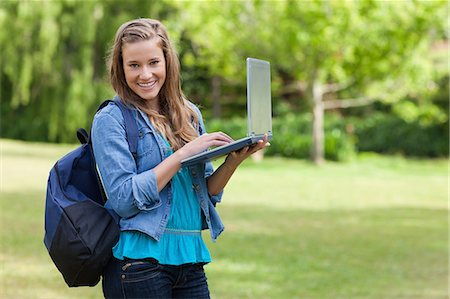 simsearch:6109-06003402,k - Young happy girl holding her laptop while standing upright in the countryside Foto de stock - Sin royalties Premium, Código: 6109-06003407