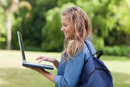 Side view of a smiling teenager holding her laptop while standing in the countryside Foto de stock - Sin royalties Premium, Código: 6109-06003411