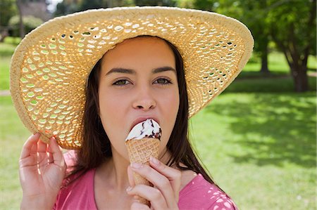 Young attractive girl eating an ice cream cone while standing in a public garden Stock Photo - Premium Royalty-Free, Code: 6109-06003423