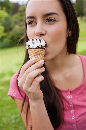 summer dessert - Young attractive woman looking away while eating an ice cream cone in a park Foto de stock - Sin royalties Premium, Código: 6109-06003421