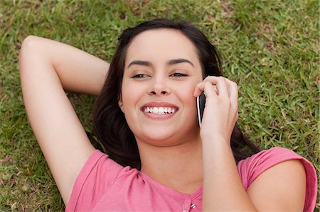 phone young caucasian woman relaxed - Overhead view of a young happy woman using her cellphone while lying on the grass Stock Photo - Premium Royalty-Free, Code: 6109-06003428