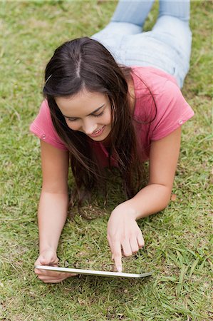 pc - Jeune femme heureuse, allongé dans un parc tout en utilisant son ordinateur tablette Photographie de stock - Premium Libres de Droits, Code: 6109-06003432