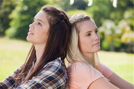 Young friends standing back to back in a public garden Stock Photo - Premium Royalty-Free, Code: 6109-06003543