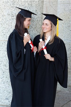 simsearch:6109-06003585,k - Young smiling graduating students looking at each other while holding their diplomas Foto de stock - Royalty Free Premium, Número: 6109-06003573