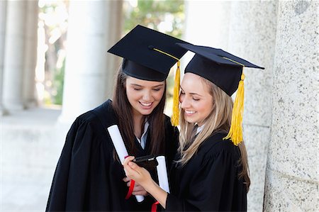simsearch:6109-06003585,k - Happy graduating students looking at a digital camera while wearing their gowns Foto de stock - Royalty Free Premium, Número: 6109-06003583