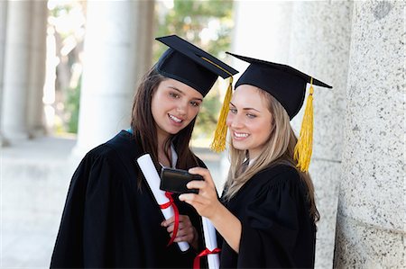 simsearch:400-07305822,k - Young smiling graduating girls photographing themselves while wearing their gowns Stock Photo - Premium Royalty-Free, Code: 6109-06003582