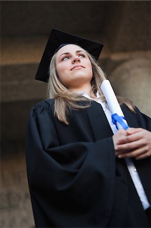 simsearch:6109-06003585,k - Low-angle view of a graduating student standing up while wearing a gown Foto de stock - Royalty Free Premium, Número: 6109-06003586