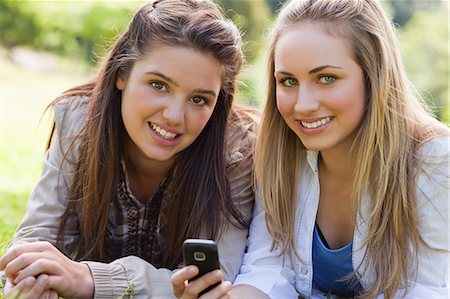 simsearch:6109-06003537,k - Young attractive girl showing her mobile phone to her best friend while looking ahead Fotografie stock - Premium Royalty-Free, Codice: 6109-06003501