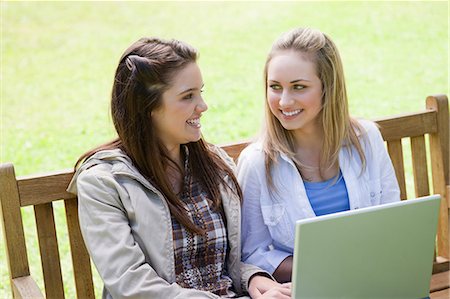 Smiling women sitting on a bench in the countryside with a laptop on their knees Stock Photo - Premium Royalty-Free, Code: 6109-06003525
