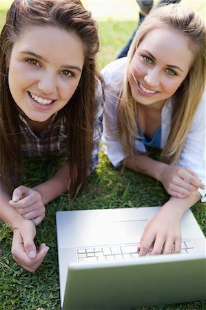 simsearch:6109-06003526,k - Young girls lying in a public garden while smiling at the camera in front of a laptop Stock Photo - Premium Royalty-Free, Code: 6109-06003535