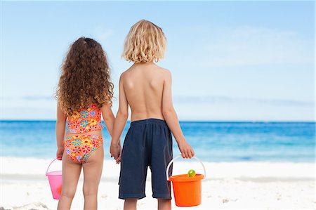 Back view of young siblings with buckets and shovels looking at the sea Stock Photo - Premium Royalty-Free, Code: 6109-06003681