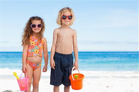 pá de jardim - Little children with sunglasses standing on the beach Foto de stock - Royalty Free Premium, Número: 6109-06003682