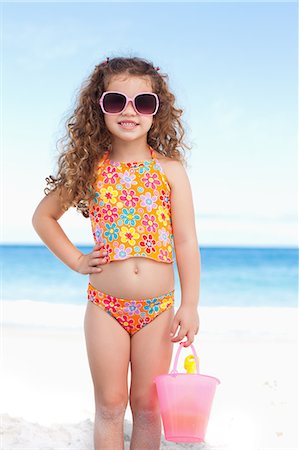 pá de jardim - Cute smiling girl with her sunglasses standing on the beach Foto de stock - Royalty Free Premium, Número: 6109-06003687