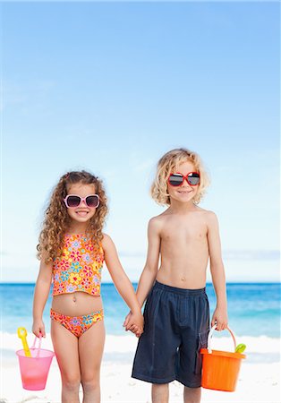 pá de jardim - Little children with sunglasses holding hands on the beach Foto de stock - Royalty Free Premium, Número: 6109-06003684