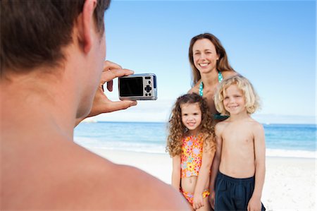 Back view of a young father with digi cam taking family pictures on teh beach Foto de stock - Sin royalties Premium, Código: 6109-06003638