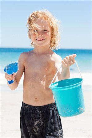 pá de jardim - Smiling little boy with his bucket and shovel at the beach Foto de stock - Royalty Free Premium, Número: 6109-06003779