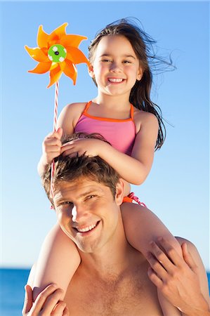 swimsuit carrying on shoulders - Smiling father at the beach with his little daughter on his shoulders Stock Photo - Premium Royalty-Free, Code: 6109-06003796