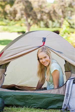 A woman almost fully inside a tent as she smiles with her head just outside the door of it Stock Photo - Premium Royalty-Free, Code: 6109-06003893