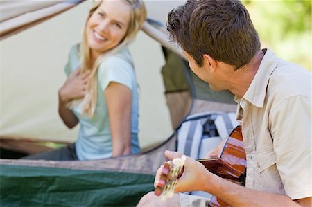 simsearch:6109-06003907,k - A man looking at his smiling girlfriend as he plays guitar for her to enjoy Stock Photo - Premium Royalty-Free, Code: 6109-06003898