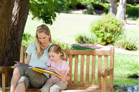 simsearch:6109-06003976,k - Reading together a mother and daughter sit on the park bench Foto de stock - Sin royalties Premium, Código: 6109-06003949