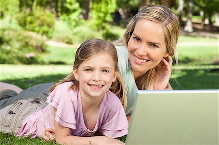 simsearch:6109-06004050,k - A mother and her daughter lying on the ground together with a laptop Foto de stock - Sin royalties Premium, Código: 6109-06003977