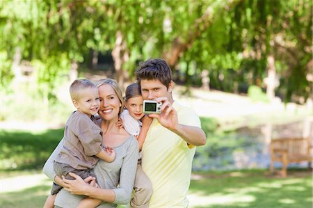 A smiling family all together to take a photo in the park Stock Photo - Premium Royalty-Free, Code: 6109-06004040