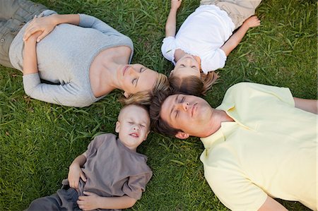A sleeping family on the ground in the park their heads all by each other Stock Photo - Premium Royalty-Free, Code: 6109-06004045