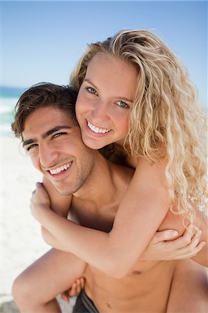 Young handsome man giving her girlfriend a piggy-back on the beach Foto de stock - Sin royalties Premium, Código: 6109-06004095