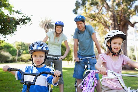 family on bicycle in park - A smiling family in the park on their bikes as they get ready to go cycling Stock Photo - Premium Royalty-Free, Code: 6109-06004033