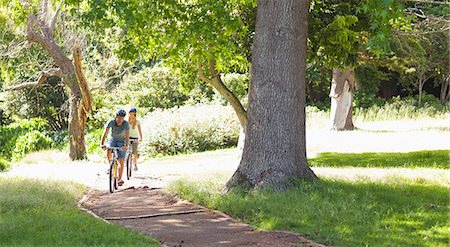 A boyfriend and girlfriend cycle together down a path Stock Photo - Premium Royalty-Free, Code: 6109-06004034