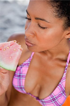 delicioso - Young relaxed woman closing her eyes while eating a delicious piece of watermelon Foto de stock - Sin royalties Premium, Código: 6109-06004169