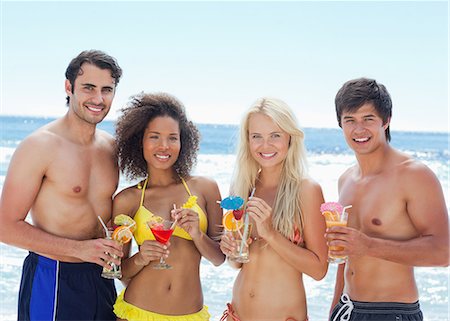 simsearch:6109-06004206,k - Two men and two women wearing swimsuits as they hold cocktails while standing on a beach Foto de stock - Sin royalties Premium, Código: 6109-06004185