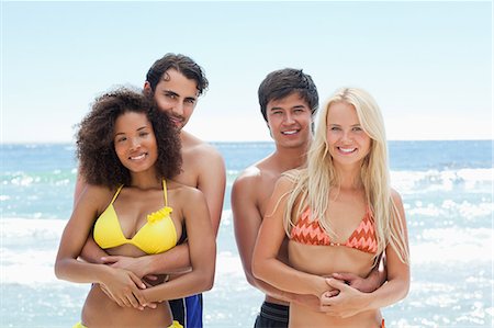 simsearch:6109-06004206,k - Two men holding their partners as they stand by the water in swimwear Foto de stock - Sin royalties Premium, Código: 6109-06004189