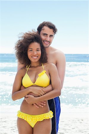 Man wearing a swimsuit smiling while he wraps his arms around his friends waist Stock Photo - Premium Royalty-Free, Code: 6109-06004191