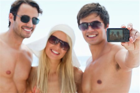 simsearch:6109-06004181,k - Two men and a woman wearing sunglasses while posing for a photo on a beach Foto de stock - Royalty Free Premium, Número: 6109-06004198