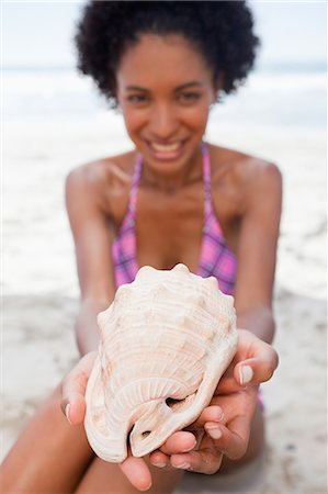 shell woman - Beautiful seashell being held by a young attractive woman on the beach Stock Photo - Premium Royalty-Free, Code: 6109-06004125