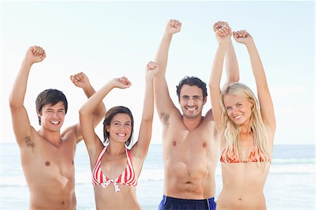 Two men and two women in swimsuits smiling as they raise their arms by the sea Foto de stock - Sin royalties Premium, Código: 6109-06004268