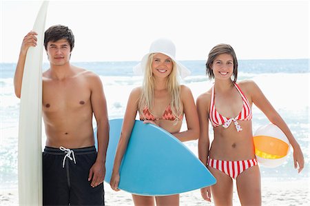 simsearch:6109-06004206,k - Two women and a man standing with surfboards in hand smiling as they are at the beach. Foto de stock - Sin royalties Premium, Código: 6109-06004200