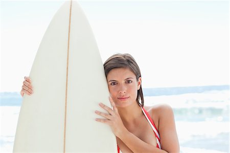 simsearch:6109-06004206,k - Woman in bikini with a serious expression holding a surfboard with two hands on the beach Foto de stock - Sin royalties Premium, Código: 6109-06004210
