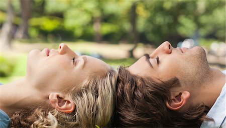 Side view of a young couple relaxing on the lawn Stock Photo - Premium Royalty-Free, Code: 6109-06004354