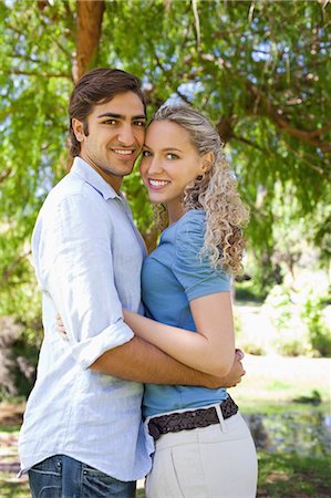 Side view of a smiling young couple hugging under a tree Stock Photo - Premium Royalty-Free, Code: 6109-06004367
