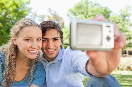 Smiling young couple in the park taking a photo of themselves Stock Photo - Premium Royalty-Free, Code: 6109-06004386