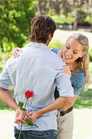 Young woman looking behind her boyfriends back to find a rose Stock Photo - Premium Royalty-Free, Code: 6109-06004339