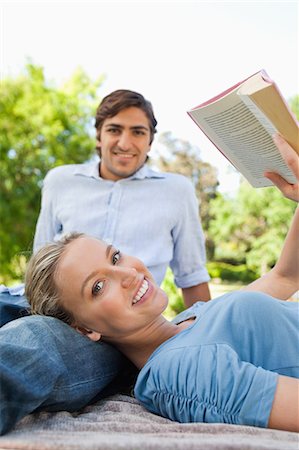 Young woman with a book leaning against her boyfriend Stock Photo - Premium Royalty-Free, Code: 6109-06004415