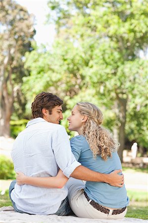 simsearch:6109-06004349,k - Rear view of a smiling young couple sitting in the park Stock Photo - Premium Royalty-Free, Code: 6109-06004431