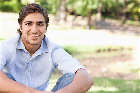 Smiling young male sitting in the park Stock Photo - Premium Royalty-Free, Code: 6109-06004505