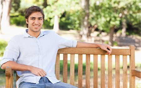Smiling young man sitting on a bench Stock Photo - Premium Royalty-Free, Code: 6109-06004511